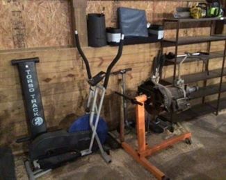 More excercise equipment among with an engine stand holding a power glide transmission. Shelving units will also be auctioned.