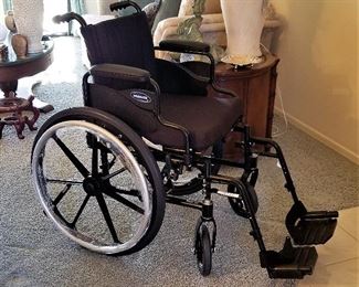 Brand new wheel chair with plastic still on wheels.