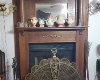 Beautiful oak fireplace mantel, 1940' brass peacock fan fireplace screen, silver plate tea set, fireplace dogs set, old books, vintage sconce lamps, Hull vases, antique crystal and glass candlestick holders