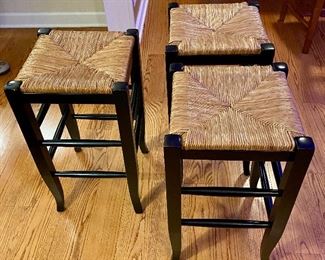 Lot 4853.  $135.00  Three Cute Pottery Barn Napoleon Backless Counter Stools - Black with Rush Seats, exc. condition, measure 26" H x 14" square - Made by Skilled Artisans from hardwood and the rush seat is woven by hand onto the frame. Classic Seat tucks nicely under counter when not in use! No Longer Available on Pottery Barn Site.