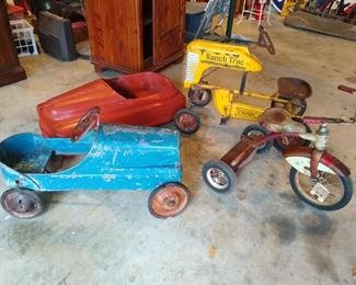 Yellow tractor, red tricycle, blue car, and top of a Buick pedal cars