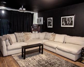 Cindy Crawford oversized sectional sofa, modern abstract pattern rug, coffee table, black and white photographs