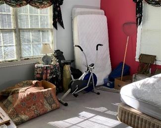 twin box springs and mattress leaning on wall, exercise bike, round table and lamp, rug