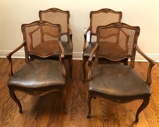 Set of 4 cane and leather dining chairs. Leather and caning is in good as found condition. Arm on one chair is broken. Other arms are loose. We have restoration resources