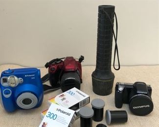 From left to right: Polariod 300 camera and three packs of 10 instant film; brand new digital Fuji FinePix S8350 24 mm camera; heavy duty flashlight, brand new Olympus SP-815UZ 14 MP, 24 mm camera with original packaging