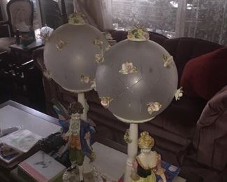 pair of porcelain lamps with glass globes , detailing one man and woman some damage to flowers 