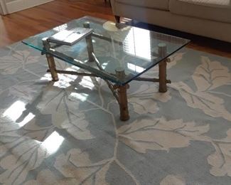 Glass-top coffee table with metal frame; large area rug with leaf motif
