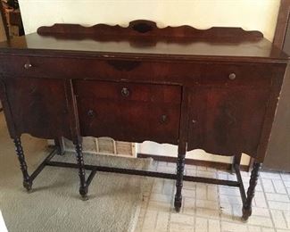 Vintage Buffet. Consists of one large drawer at the top, 2 in the middle, and a door on either side. Measures approximately 59 inches x 21x 42 tall. Two knobs door knobs are missing and has bumps and scratches due to age and usage. 
