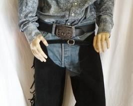 1187	MALE MANNEQUIN CLOTHED IN LEVIS JEANS, BELT W/ LEVIS BELT BUCKLE, WRANGLER WESTERN SHIRT, BANDANNA, & CHAPS. APP. 66 IN TALL. MANNEQUIN MAY SUFFER LOSSES TO BODY/FACE
