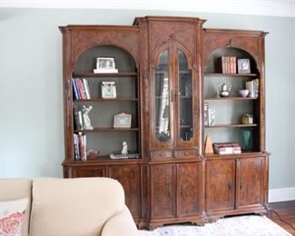 An antique burlwood library with center display behind glass
