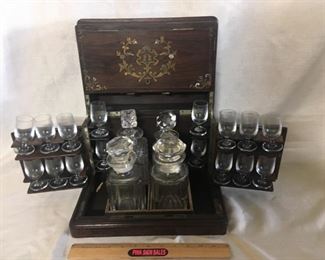 Bar. Box has brass and mother of pearl inlay. The 16 glasses all match. The four decanters do not match. Two have some damage.