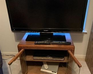 Sharp flat screen TV, Sharp Blue Ray/DVD player,  another DVD player, TV stand