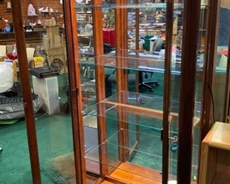 Lot 5013.  $475.00  Beautiful Howard Miller branded Cherry wood and glass display case w/ light and key.  Howard Miller sign could potentially be removed. Features  5 glass shelves and light that makes this a great piece for home, Office or Store.  32 1/2" W x 14 1/2" D x 76" H