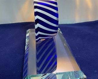 Lot 5082.  $275.00    2 Gorgeous Pieces of Harrie Glass, the first is a  STUNNING Flame in blues, purple, and clear 9.5" H  x 3" W.  The second piece is a blue and clear Ellipse on base 6" Wx 3.25" D. I was able to find these same flame online fetching $400 and an ellipse without the base for $165. So our price is a STEAL for both pieces.