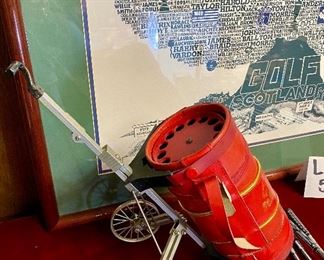 Lot 5141. $75.00. History of Golf Framed Art. Hand Signed C. Burton 1988. Signed and Numbered,  #944/1000. AND Novelty MINIATURE Golf clubs and Cart w/steel shafts Including 4 woods, Irons, Sand wedge and putter and a bag on wheels. Balls too.  Scotch Whisky or Old Andrews label on the bag.  Nice addition to your man cave!