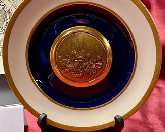 Lot 5145. $80.00. Very Cool Chicago Lot. T. Chamness Landmark Ink Art (18.5" H  x 14.25" W  has a plexiglass front, probably needs a piece of glass in there). A Wooden Medallion of Chicago Landmarks by Kurt Mager (6.25" diameter ).  A City of Chicago Crest clock with a hinge to reveal a clock (3"). The Medallion Plate by Pickard w/metal art by Kurt Mager (same art as the wooden medallion. 