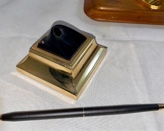 Lot 5146. $48.00  Desk Accessories; Gold Tone letter opener, gold tone Kleenex holder,  Chicago spinning medallion on a wood base, and a Cross ballpoint pen with brass stand. 