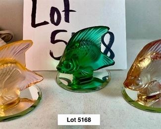 Lot 5168. $125.00. This lot includes 3 Lalique Paris Angel Fish. The fish are in Peach, Teal, and Pink w/3 small mirrored discs. Also included are 3 suede Lalique drawstring bags and only 2 Lalique boxes. The wooden stand isn't included. 