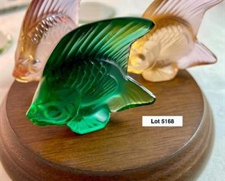 Lot 5168. $125.00. This lot includes 3 Lalique Paris Angel Fish. The fish are in Peach, Teal, and Pink w/3 small mirrored discs. Also included are 3 suede Lalique drawstring bags and only 2 Lalique boxes. The wooden stand isn't included. 