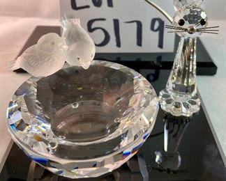 Lot 5179. $28.00. Swarovski Crystal Zoo Cat closely watching 2 birds on a birdbath (one of the birds was reattached to piece). Cat is 2.75"h x 1"w with a flexible tail.  Bird Bath: 2/5"h x 3"w. Both pieces are signed. Sold as-is.