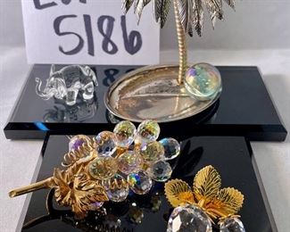 Lot 5186. $90.00. Crystal fun! Swarovski Crystal grape cluster, created as part of the "Sparkling Fruit" theme, faceted clear crystal grapes with gold plated leaves and a stem tip. Swarovski Crystal Strawberry Pin or Pendant with gold-tone leaves, An Unsigned mini elephant, crystal marble, and a trinket tray with a metal palm tree to round out the mix. 