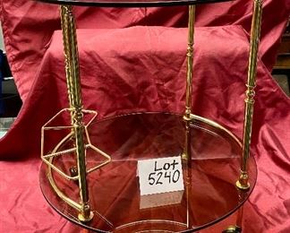 Lot 5240. $175.00 Vintage MCM Bar Cart on rubber castors. Brass and dark smoked glass, 2 tier with 3 bottle holders on the lower level. 27.5" H x 22"diameter. Handle to Handle: 23" W.  
