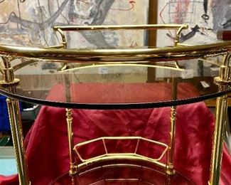 Lot 5240. $175.00 Vintage MCM Bar Cart on rubber castors. Brass and dark smoked glass, 2 tier with 3 bottle holders on the lower level. 27.5" H x 22"diameter. Handle to Handle: 23" W