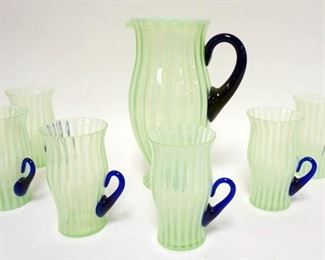 1040	FENTON GREEN OPALESCENT STRIP 7 PIECE LEMONADE SET WITH APPLIED COBALT BLUE HANDLES. PITCHER IS 10 IN HIGH, TUMBLERS ARE 5 1/4 IN HIGH. 4 TUMBLERS HAVE PIN NICKS ON THE RIMS
