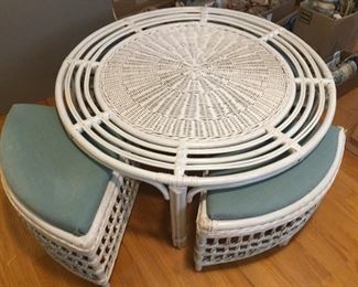 Round white rattan table with three seats.