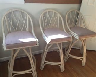 Three rattan chairs with cushions.