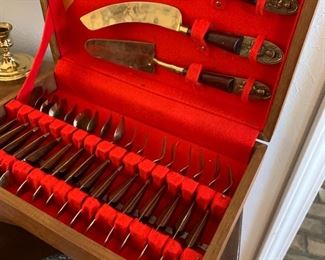 These are super cool. Flatware set from what is now Thailand, these were super popular in the late 60's and 70's.  A ton of them were brought home to America by GI's during Vietnam.  The flatware itself is bronze with an image of Buddah on the end of the handle, and the handles is made of rosewood - which is actually banned for international trade because it's an endangered species.  The more you know.