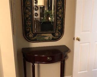 mahogany demilune table below painted mirror