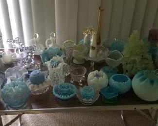 this picture shows some of the glass ware ranging from rose bowls to blueberry  dishes, swirl bowl from the 1800's or early 1900's, a Spanish lace vase, art glass vase with a ruffled top, a Belleek dish, a Fenton blue opalescent rose bowl and many other pieces