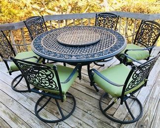Cast aluminum patio furniture. Comes with a large table with a lazy Susan in the center, 6 swivel/rocker chairs, and sunbrella cushions. 