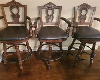 Three beautiful barstools from Ashley Furniture North Shore collection. Barstools have faux leather seats with ornate carved wooden back and arms and swivel.

Measures 22" x 22" x 46". https://ctbids.com/#!/description/share/752995