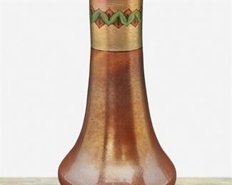 18
A L.C. Tiffany "Tel El-Amarna" Favrile Glass Vase
1912; New York, NY
Signed: L.C. Tiffany / Favrile / 8715 G
The flared Favrile glass vase with brown iridescent body and gold iridescent neck shaded to blue and decorated with green and ochre geometric "Tel el-Amarna" design
9" H x 4.25" Dia.
Estimate: $1,000 - $1,500