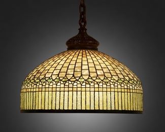 24
A Tiffany Studios "Curtain Border" Hanging Lamp
Circa 1902-1919; New York, NY
Signed: Tiffany Studios / New York / 1515-39
The yellow leaded glass domical shade with green diamond band and curtain-style border fitted with a six-light socket cluster, patinated bronze heat cap and suspended chain link harness, and verdigris patinated bronze rims, electrified
13" H x 24" Dia.
Estimate: $20,000 - $30,000