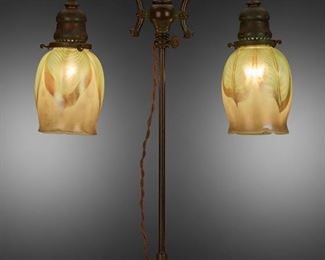 41
A Tiffany Studios Double-Arm Table Lamp
Circa 1902-1919; New York, NY
Shades signed: L.C.T.; Base signed: Tiffany Studios / New York / 304
The two green and gold iridescent Favrile glass floriform shades with pulled feather motif on a patinated bronze double-arm, adjustable armature base with verdigris patination and engraved foliate and teardrop motifs, electrified
Overall: 20" H x 13.5" Dia.
Estimate: $4,000 - $6,000