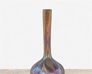 44
A L.C. Tiffany Favrile Glass Bud Vase
Circa 1892-1902; New York, NY
Signed: X 1885 / [T.G.D.Co. paper label]
The brown iridescent Favrile glass vase with bulbous base, slender cylindrical stem, and polychrome pulled feather motif
6.75" H x 3.25" Dia.
Estimate: $600 - $800