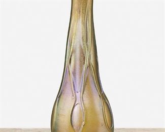 45
A L.C. Tiffany Favrile Glass Free-Form Vase
1902; New York, NY
Signed: L.C.T. / R 5519
The gold iridescent Favrile glass vase shaded to blue with tapered free-form body and low relief rippled exterior
9.5" H x 3.5" Dia.
Estimate: $500 - $700