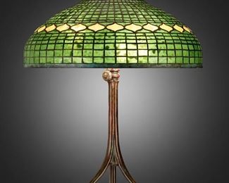 64
A Tiffany Studios "Vine Border" Table Lamp
Circa 1902-1919; New York, NY
Shade signed: Tiffany Studios / New York; Base spuriously signed: Tiffany Studios / New York / 393
The green and yellow leaded glass "Vine Border" shade on a six-light patinated bronze Tiffany-style reproduction base in the form of three spreading root nodes, electrified
Overall: 29" H x 20.5" Dia.
Estimate: $4,000 - $6,000