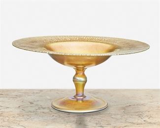 67
A L.C. Tiffany Favrile Glass Compote
First-quarter 20th Century; New York, NY
Signed: L.C.T. / Favrile
The gold iridescent Favrile glass compote with heavy onion skin to rim
6" H x 12.5" Dia.
Estimate: $1,000 - $1,500