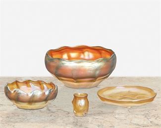 70
Four L.C. Tiffany Favrile Glass Items
First-quarter 20th Century; New York, NY
Two signed: L.C.T. / Favrile; One signed: L.C.T. / M 9153; One signed: L.C.T. M 2222
Each gold shaded to blue iridescent Favrile glass, comprising a large bowl with gently scalloped edge and ribbed exterior, a finger bowl with scalloped edge and ribbed exterior, an ice plate with pigtail decorations, and a toothpick holder with pigtail decorations, 4 pieces
Largest: 3" H x 6.25" Dia.; Smallest: 2" H x 1.5" Dia.
Estimate: $600 - $800