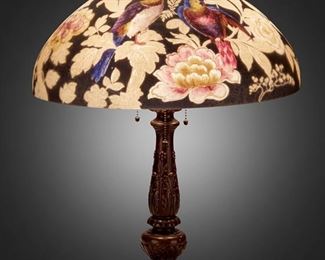 103
A Handel Reverse-Painted Glass "Parrot" Table Lamp
Circa 1923; Meriden, Connecticut
Shade signed: Handel / Pat'd. No. 979664 / Handel / 7023; Base signed: Handel
The domical, chipped ice finished glass shade with reverse-painted blue and orange parrots and a butterfly among pink and white peonies against a dark charcoal ground on a three-light patinated metal base with knopped column, gadrooning, daisy motifs, and circular foot, electrified
Overall: 24.5" H x 18" Dia.
Estimate: $4,000 - $6,000
