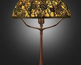 133
A Tiffany Studios "Grape Vine" Filigree Table Lamp
Circa 1902-1919; New York, NY
Shade signed: Tiffany Studios / New York; Base signed: Tiffany Studios / New York / 436
The shade with verdigris patinated bronze grape vine motif overlay set against polychrome slag glass panels on a single-light patinated bronze base with ring holder, square foot, and plain column, electrified
Overall: 21.5" H x 14" Dia.
Estimate: $5,000 - $7,000