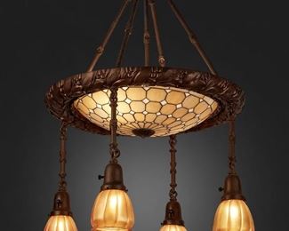 138
A Leaded Glass And Patinated Metal Chandelier
First-quarter 20th Century
Three shades signed: Quezal; Fixture signed: Horn and Brannen Mfg. Co. / Philadelphia
The two-light patinated metal chandelier with a caramel-colored geometric leaded glass shade enclosed in a wreath-style metal border issuing four drop pendants with gold iridescent Quezal floriform glass shades and reeded hanging shafts, electrified
32" H x 21" Dia.
Estimate: $2,000 - $3,000
