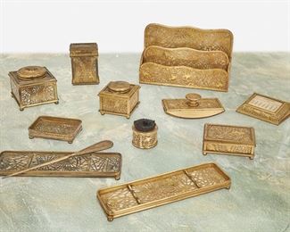 141
A Tiffany Studios Gilt-Bronze Pine Needle Desk Set
Circa 1902-1919; New York, NY
Each signed: Tiffany Studios / New York; Further marked: 800 / 844 / 845 / 876 / 930 / 969 / 977 / 981 / 995 / 1004 / 1008
Each white and amber mottled glass with gilt-bronze pine needle motif overlay, comprising a paper rack, two pen trays, a rocker blotter, a paperweight calendar, a card case, a large inkwell, a small inkwell, a small lidded box, an ashtray, a paper knife, and a pen wiper, 12 pieces
Largest: 6.25" H x 10" W x 2.5" D; Smallest: 1.75" H x 1.125" Dia.
Estimate: $1,500 - $2,500