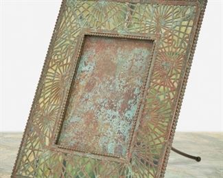 142
A Tiffany Studios Bronze Pine Needle Frame
Circa 1902-1919; New York, NY
Signed: Tiffany Studios / New York / 947
The rectangular verdigris patinated bronze frame with green glass, pine needle motif bronze overlay, and beaded border enclosing a rectangular opening
Overall: 9.5" H x 8" W x 6" D; Opening: 5.375" H x 3.875" W
Estimate: $1,000 - $1,500