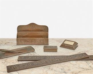 150
A Tiffany Studios "Zodiac" Desk Set
Circa 1902-1919; New York, NY
Each signed: Tiffany Studios / New York; Further marked: 802 / 929 / 988 /1000 / 1009 / 1095
Each patinated bronze with "Zodiac" motif depicting the astrological signs in cartouches surrounded by interlace, comprising a paper rack, two large blotter ends, a pen tray, a paperweight calendar, a paper knife, and a stamp box, 7 pieces
Largest: 6.25" H x 9.5" W x 2.25" D; Smallest: 1" H x 3.75" W x 2" D
Estimate: $1,000 - $1,500