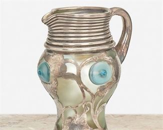 209
An Art Nouveau Loetz-Style Sterling Silver Overlay Glass Pitcher
Late 19th/early 20th Century
Stamped: Sterling
The iridescent green frosted glass pitcher with blue prunts and sterling silver handle, threaded neck, and leaf motif overlay
6.75" H x 5.25" W x 4.75" D
18.655 gross oz. troy approximately
Estimate: $600 - $800